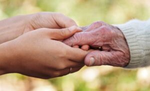 mano di un assistente stringe la mano di una persona anziana