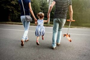 Una bambina attraversa la strada con i genitori