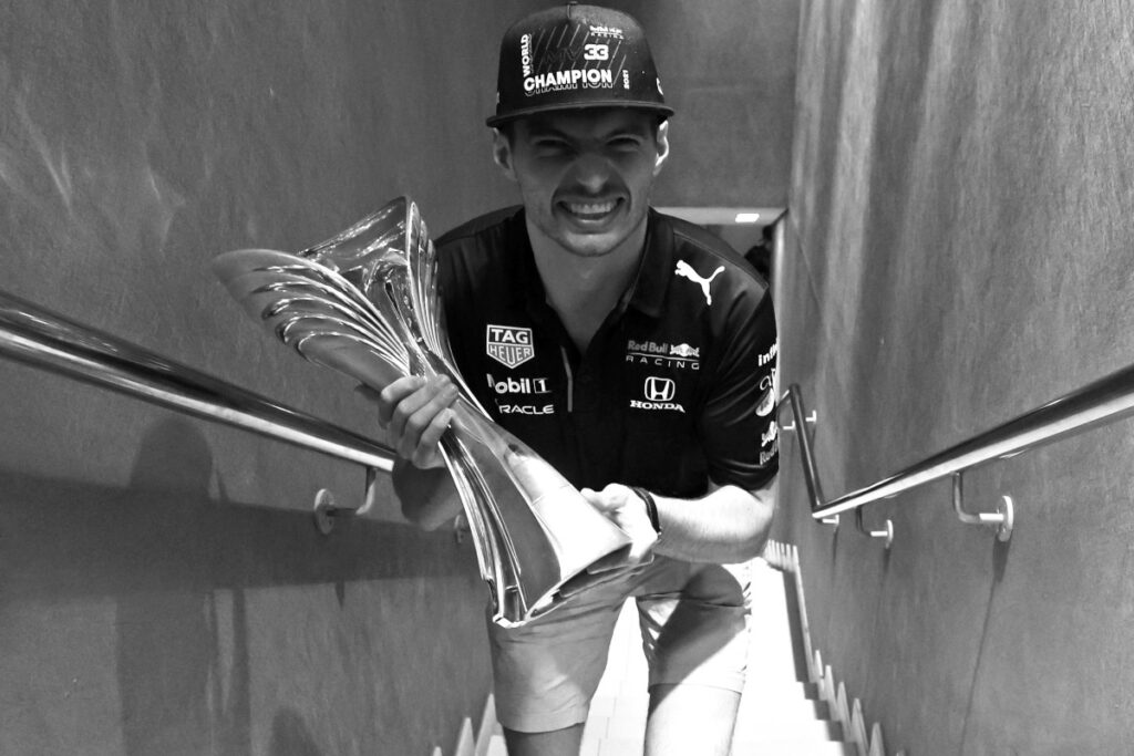 Max Verstappen sorridente con il trofeo della vittoria del mondiale di Formula 1