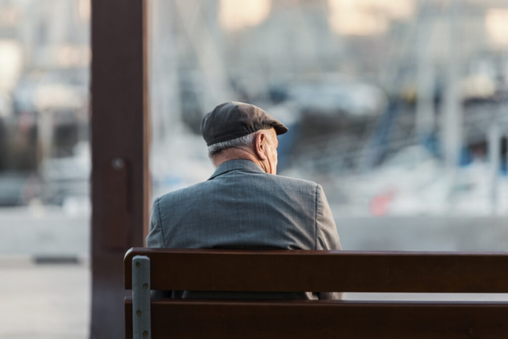 anziano solo su una panchina di spalle