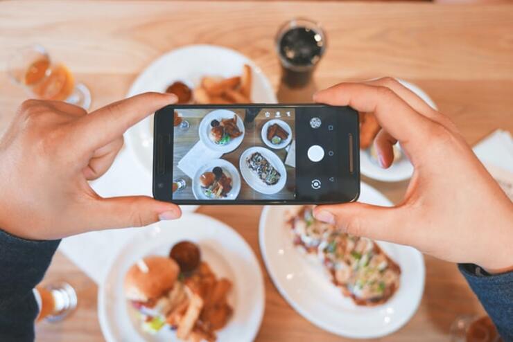 Foto di persona che scatta foto a piatti con smartphone