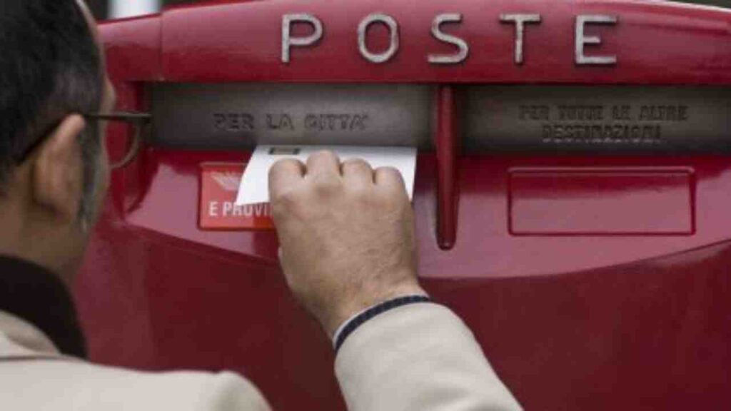 Un uomo spedisce una lettera presso una cassetta della posta