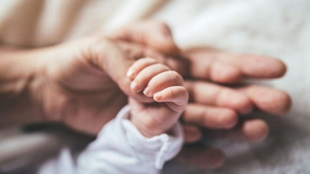 Una foto delle mani di un genitore e un figlio