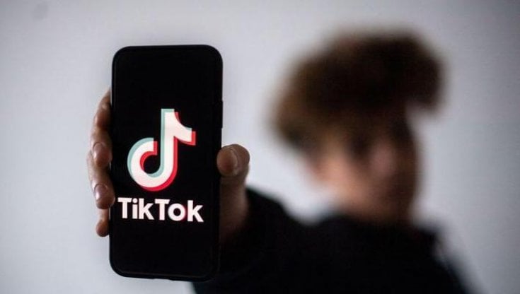 Un ragazzo con in mano un telofonino con il logo di TikTok