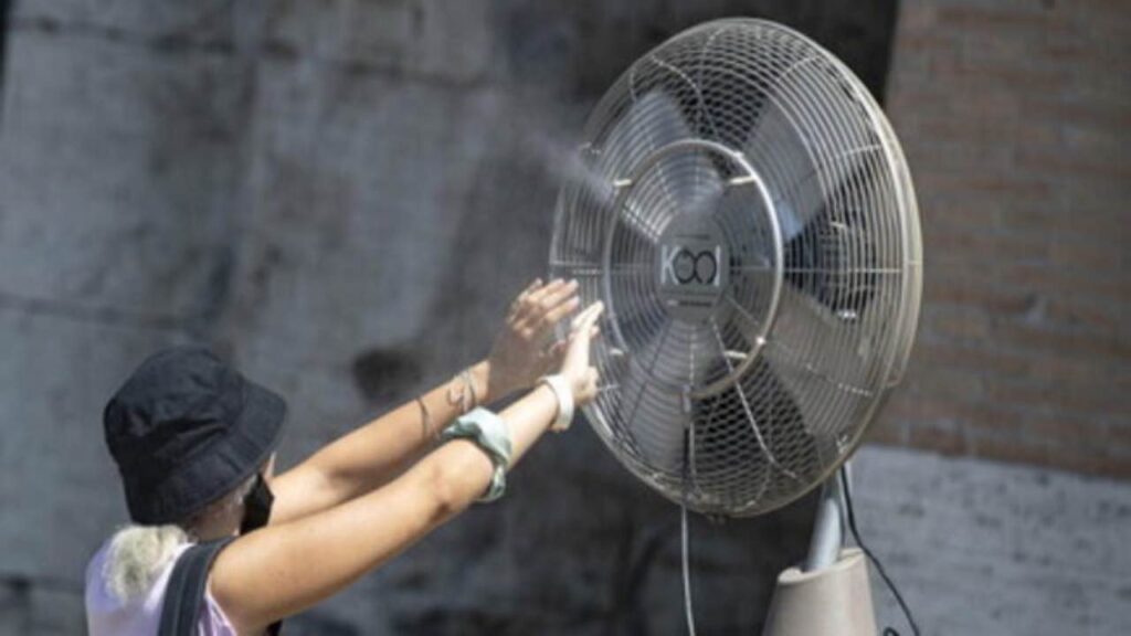 Una ragazza trova refrigerio dal caldo in un ventilatore