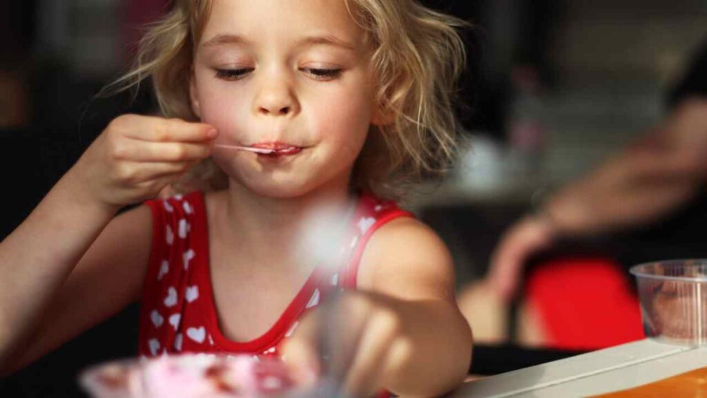 Una bambina mangia un gelato al ristorante