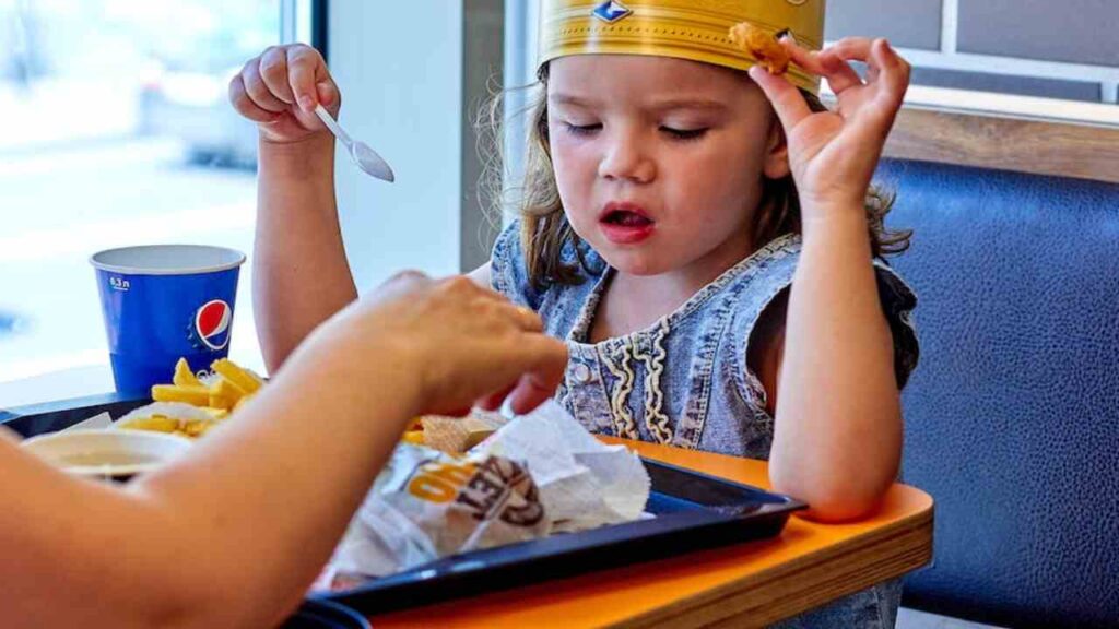 Una bambina che pranza in un fast food
