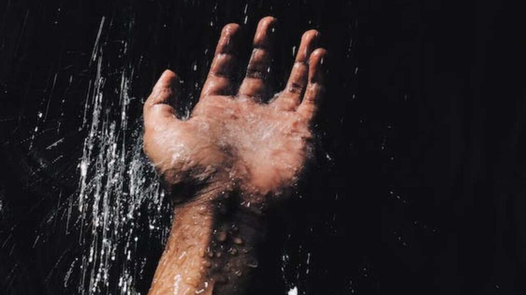 Una mano di un uomo sotto la doccia