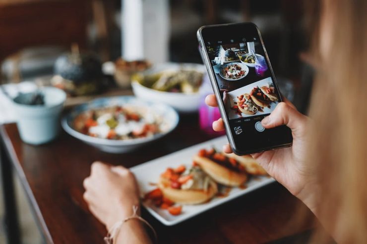 Una ragazza fotografa i piatti a tavola