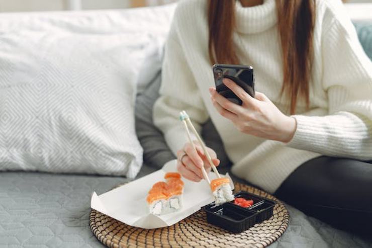 Una ragazza che fotografa un piatto di sushi