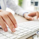 Mano che digita su tastiera al computer