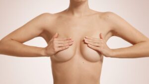 Busto donna nuda con seno tra le mani