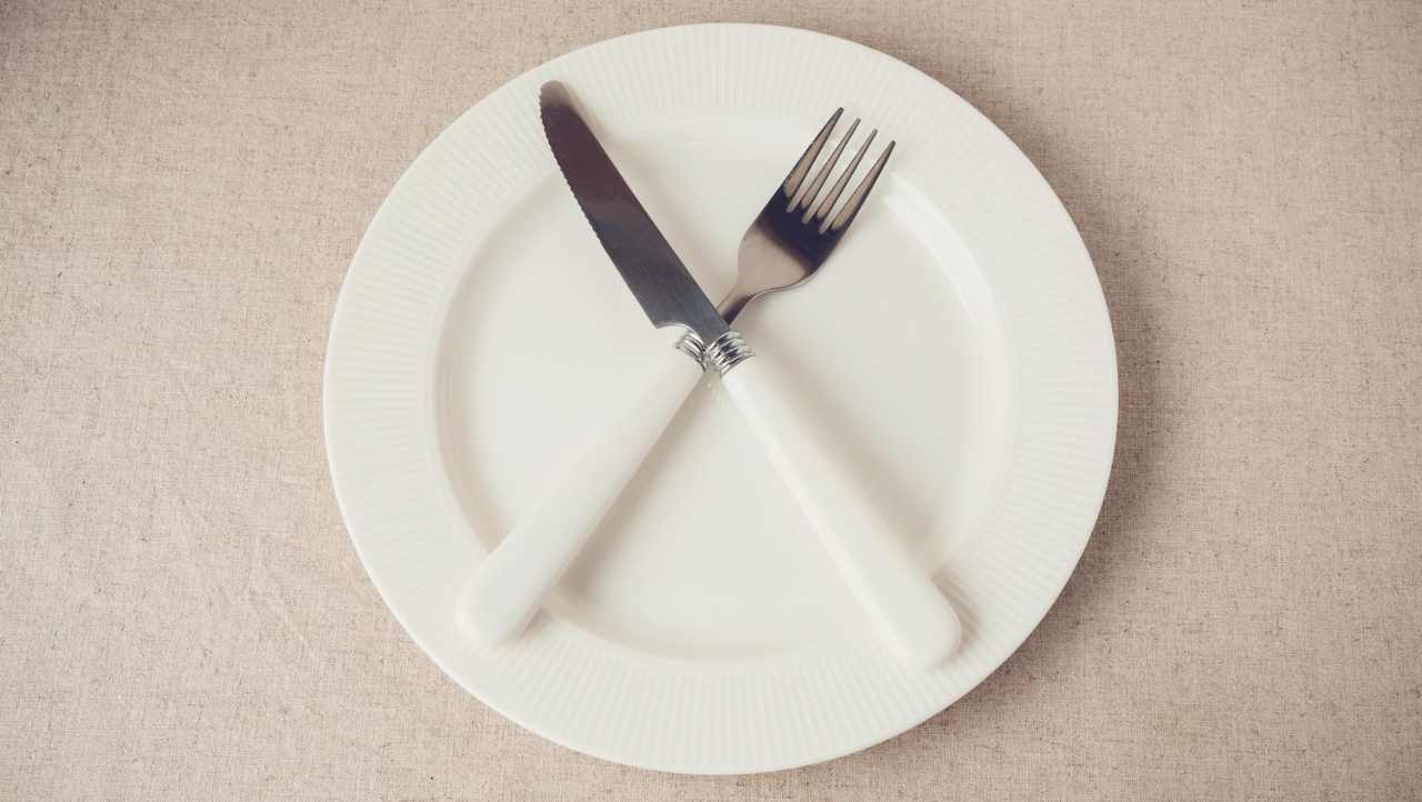 Forchetta e coltello incrociati su piatto vuoto