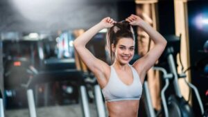 Ragazza in palestra si lega i capelli sorridente