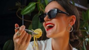 Una ragazza sorride mangiando un piatto di pasta