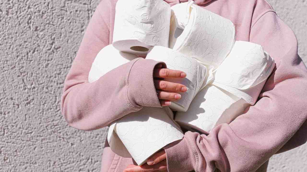 Una donna tiene in mano diversi rotoli di carta igienica