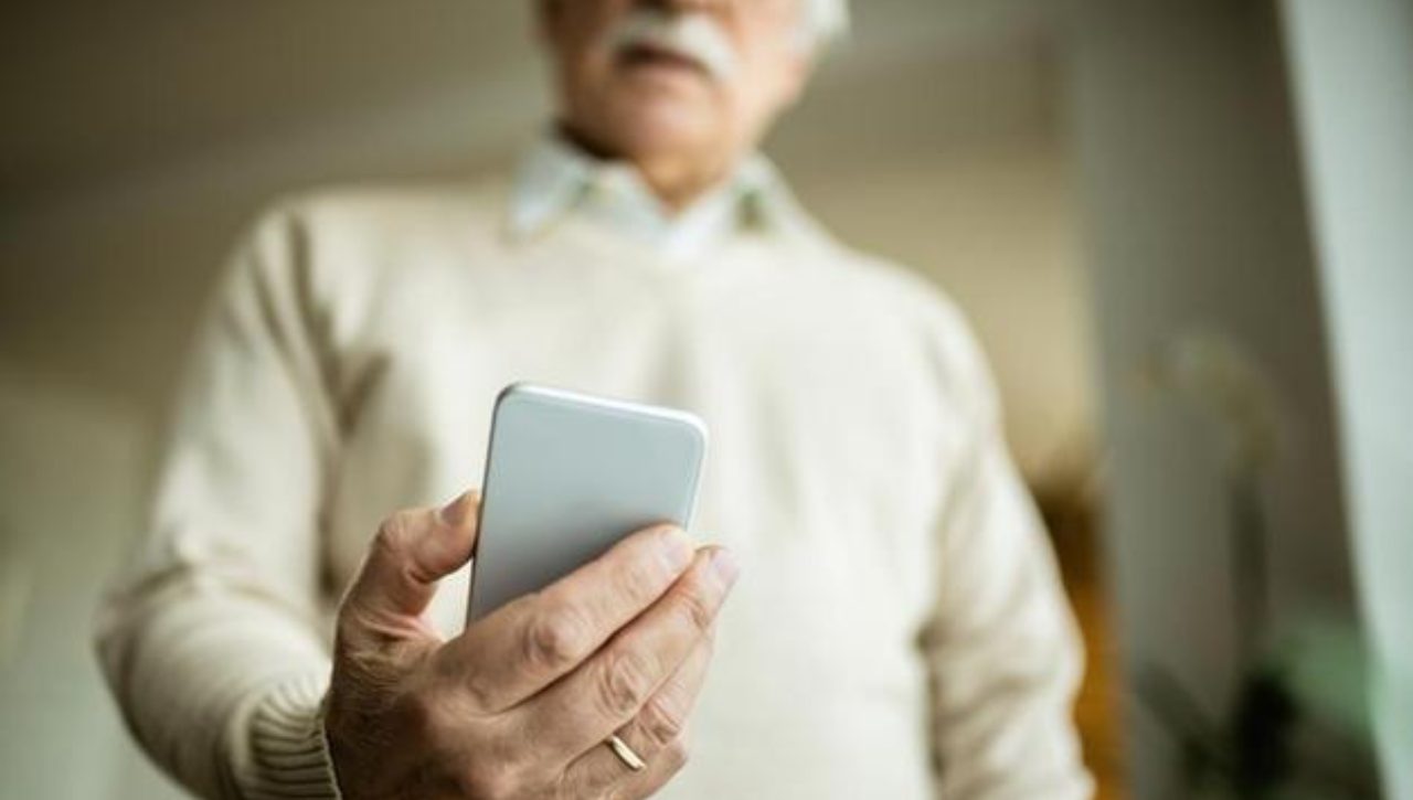 Anziano al telefono guarda lo smartphone