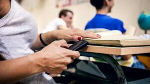 Una studentessa in classe con cellulare in mano