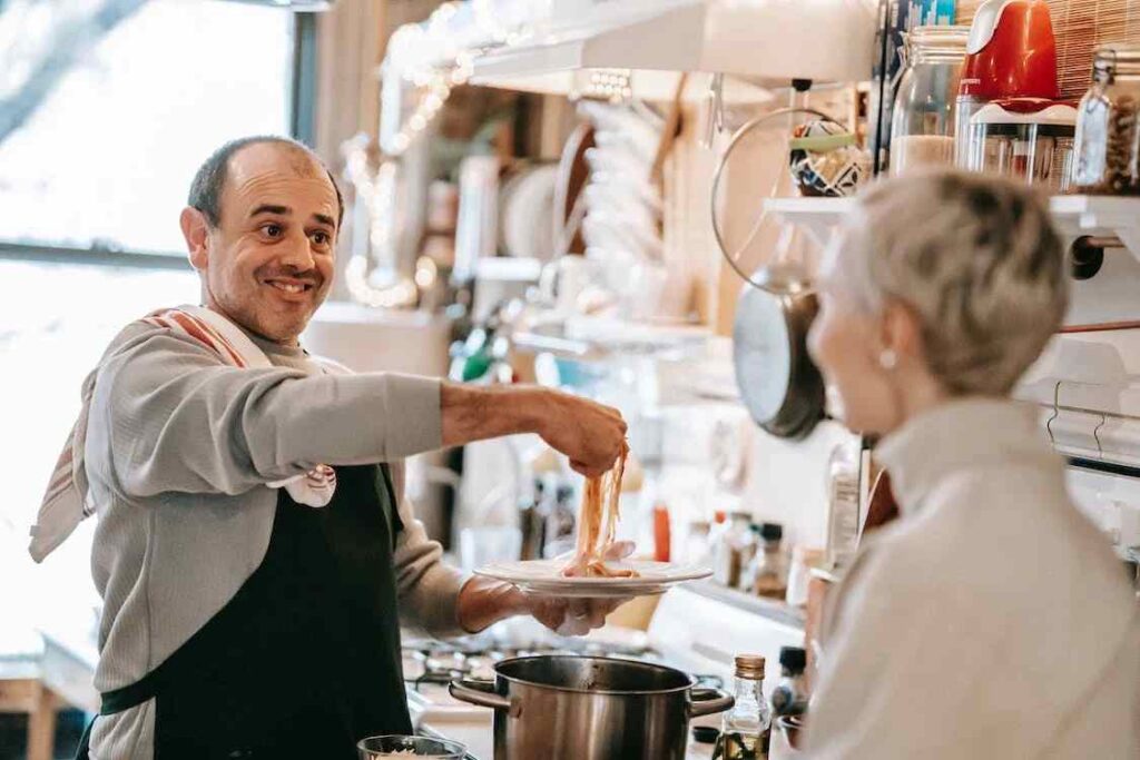 Due persone cucinano pasta e sono felici