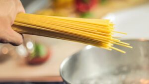 Un uomo intento a cucinare degli spaghetti