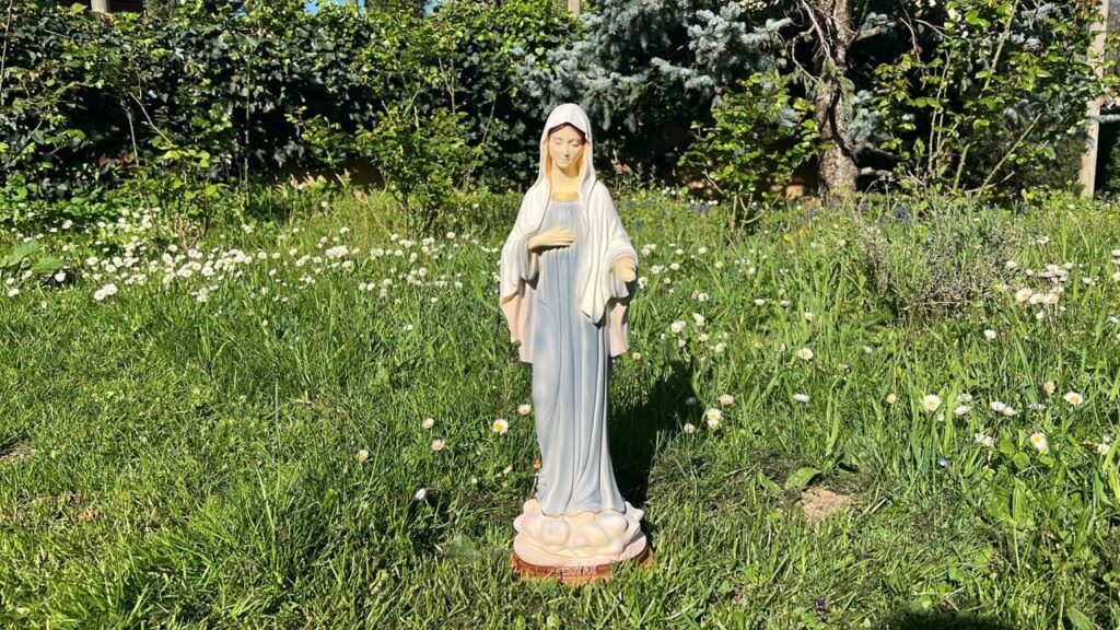 Maria, statua della Madonnina in un prato