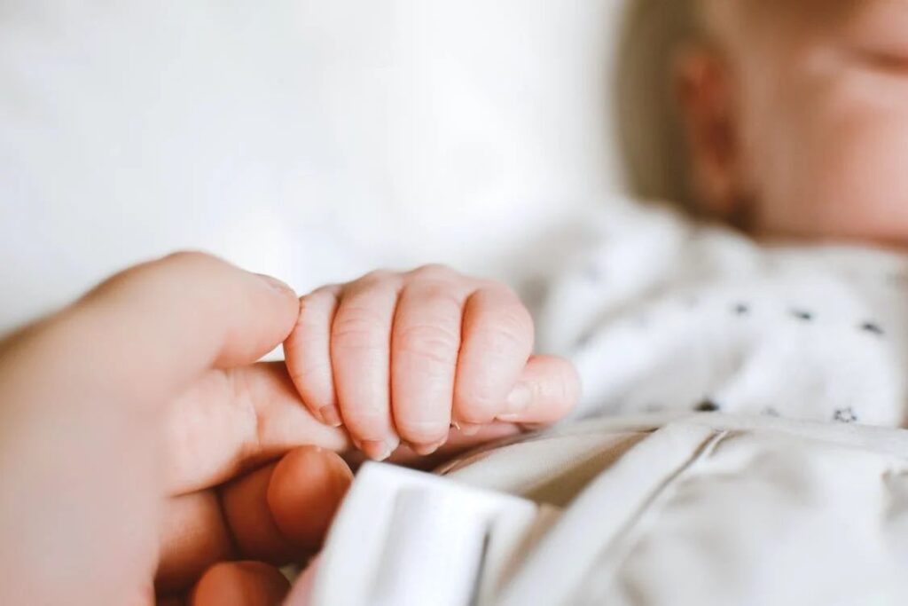 Un neonato che tiene la mano a sua mamma