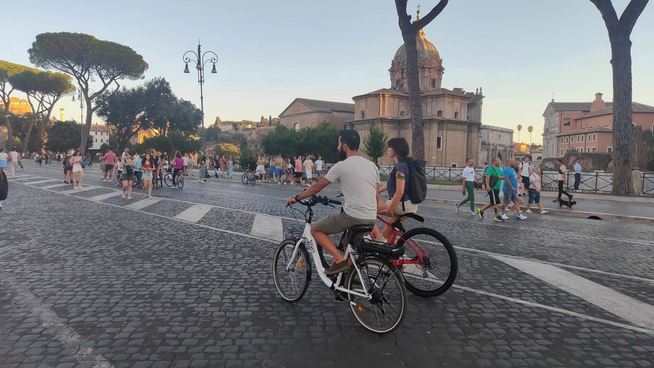 Persone a passeggio e in bicicletta in via dei Fori Imperiali a Roma