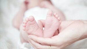Un neonato afferrato per i piedi da una mano di una mamma