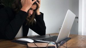 Donna con le mani nei capelli davanti il pc