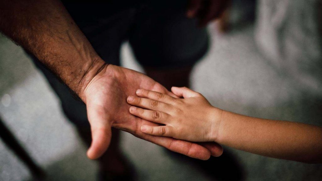 La mano di un papà e la mano di un bambino