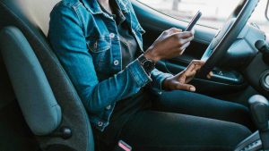 Donna alla guida con lo smartphone, pexels, rdne